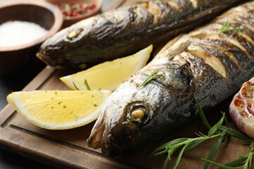 Tasty roasted seabass fish served with rosemary and lemon on grey table, closeup. Homemade seafood...