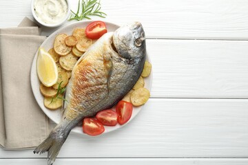 Homemade seafood dish. Tasty roasted dorado fish served with vegetables and sauce on white wooden table, flat lay. Space for text