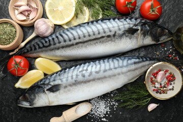 Fresh raw mackerels and spices on black table, flat lay. Seafood delicacies