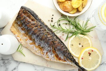 Tasty roasted mackerel served with spices and potatoes on white marble table, flat lay. Homemade seafood dish