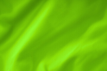 Neon lime green fabric with soft folds , textile texture close-up
