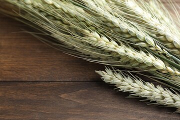 Many green wheat spikes on wooden table, closeup. Space for text