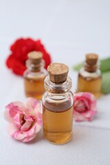 Bottles of cosmetic products and roses on white table, closeup