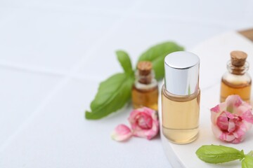 Bottles of cosmetic products, roses and basil on white table, closeup. Space for text