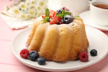 Delicious bundt cake with powdered sugar, berries and mint on pink wooden table, closeup