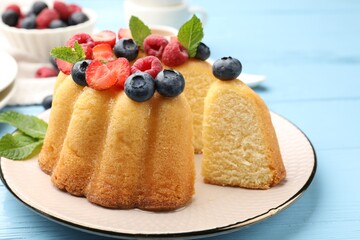 Tasty Bundt cake with berries and mint on light blue wooden table, closeup