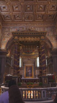 Santa Maria Maggiore, ROME, ITALY, AUGUST 20th, 2025 - Golden altar and ornate baldachin inside Basilica di Santa Maria Maggiore with worshippers admiring sacred decorations
