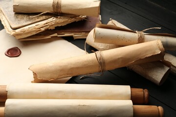 Many old rolled scrolls on black wooden table, closeup