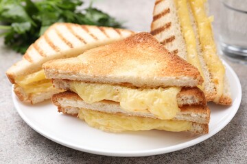 Tasty sandwiches with melted cheese and parsley on grey table, closeup