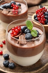 Delicious panna cotta with chocolate, berries and mint on table, closeup
