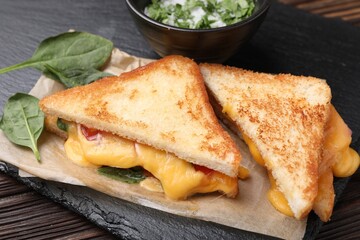 Delicious sandwiches with melted cheese and spinach on wooden table