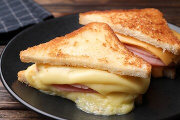 Delicious sandwiches with melted cheese and ham on wooden table, closeup
