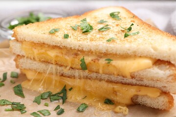 Delicious sandwiches with melted cheese and parsley on table, closeup