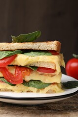Delicious sandwiches with melted cheese, spinach and tomatoes on wooden table, closeup