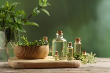 Bottles of essential oils and different herbs on wooden table outdoors