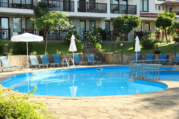 Outdoor swimming pool and sunbeds near hotel at luxury resort