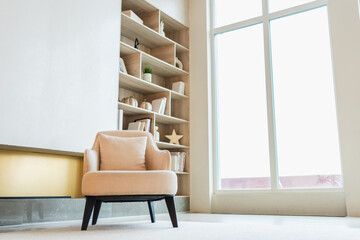 Stylish loft living room interior. Spacious design apartment with light white walls large window beige chair armchair. Clean modern decoration with elegant furniture in minimalist Scandinavian style