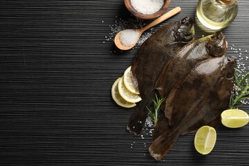 Fresh flounder fish, salt and products on black wooden table, flat lay with space for text. Raw...