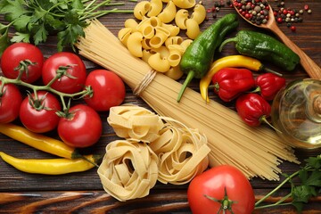 Different types of pasta and ingredients on wooden table, flat lay