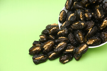 Dried ajwa dates (Khajoor) on a green background are food for breaking the fast during the Islamic...
