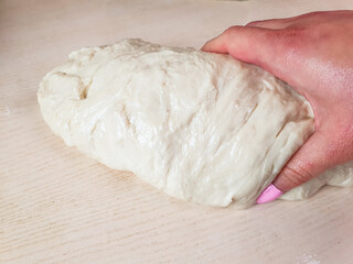 Kneading dough, preparing dough for baking a pie, women's hands kneading natural dough