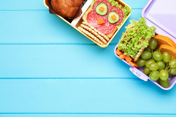 Open lunch boxes with tasty food on light blue wooden table, flat lay and space for text. Back to school