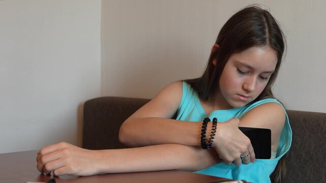 Girl with diabetes checking blood glucose level at home using continuous glucose monitor. The girl checks the glucose level