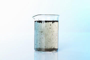 Glass beaker with dirty water on mirror surface