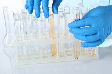 Examination of water quality. Scientist with test tubes of samples at table against light background, closeup