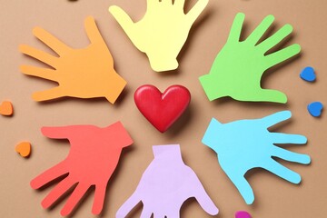 Tolerance concept. Colorful paper hands and hearts on brown background, flat lay
