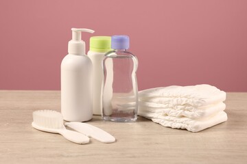 Baby accessories and bathing products on wooden table against pink background