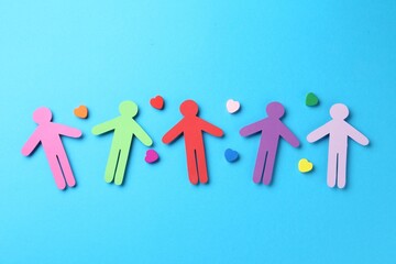 Tolerance concept. Colorful human figures and hearts on light blue background, flat lay