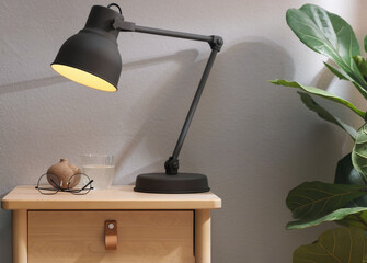 Wooden side table with glass of water, lamp and glasses indoors, closeup
