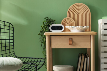 Wooden side table with stylish decor near green wall indoors, closeup