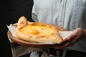 Woman with delicious khachapuri on black background, closeup