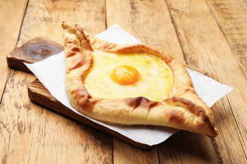 Tasty khachapuri with cheese and egg on wooden table, closeup