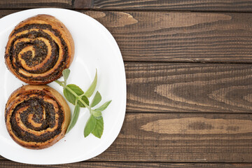 Close-up of spiral poppy seed rolls on wooden table. Homemade pastry dessert with rich filling,...