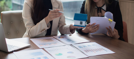 Asian female real estate businesswoman in suit smiling while advising clients on insurance, trusts, finance and successful contract agreements.