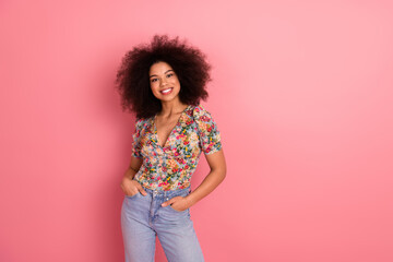 Smiling young woman with natural curls in casual stylish outfit on vibrant pink background