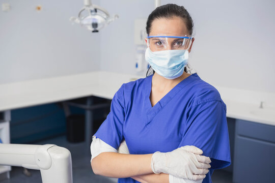 dentist wearing mask and gloves is adjusting overhead light over dental chair in operatory