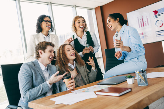 Diverse group of professionals enjoying a lively and collaborative moment in a modern office environment