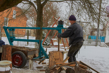 senior man chopping wood, senior man chopping wood with a mechanical wood splitter in winter in the yard