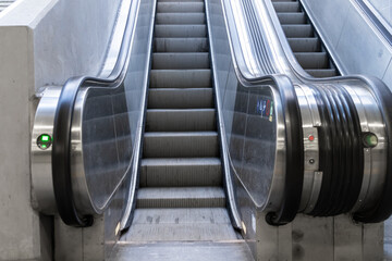 Contemporary escalators with polished metallic steps and bright handrails smoothly ascend within a...
