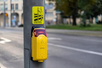Yellow pedestrian crossing button with a WAIT signal and PRESS THE BUTTON instruction on a city...
