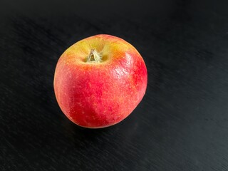 Fresh red apple resting on dark wooden surface