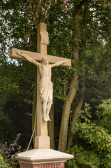 Stone statue of jesus christ on the cross in front of trees