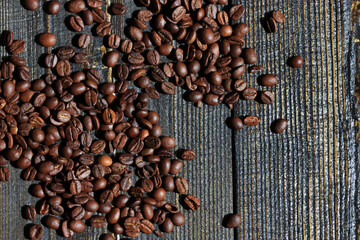 Close-up of roasted coffee beans scattered on a wooden surface