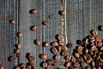 Close-up of roasted coffee beans scattered on a wooden surface