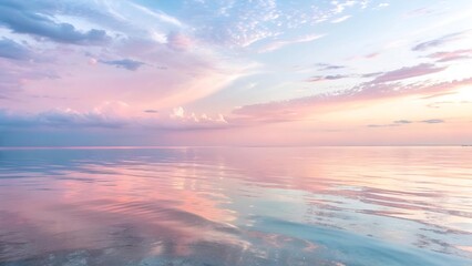 Fototapeta premium Pastel sunset over calm ocean water with soft clouds reflection