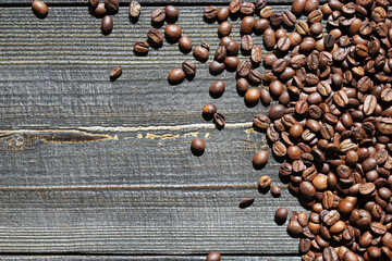 Close-up of roasted coffee beans scattered on a wooden surface